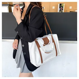 Close-up of stylish canvas tote bag with brown leather handles and fashion logo detail
