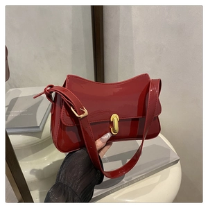 Detail of red patent leather handbag with gold metal lock and polished glossy finish