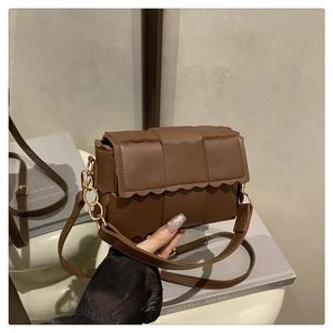 Détail du sac en similicuir tressé marron avec rabat festonné et chaîne dorée