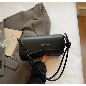 Detail of black leather shoulder bag with knotted strap and gold hardware accents