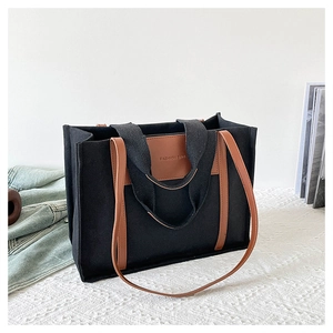 Detail of canvas tote bag with leather handles and fashion bag text on white cloth