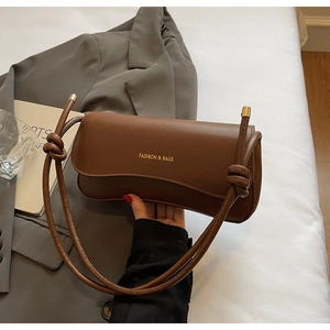 Close-up of brown leather shoulder bag with gold logo and stylish knotted strap detail