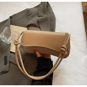 Detail view of khaki baguette bag with knotted shoulder strap and gold lettering logo