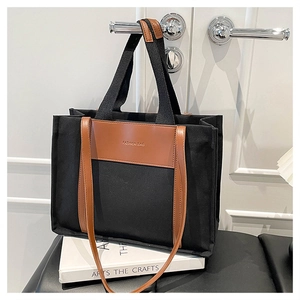 Detail of canvas tote bag with brown leather handles and adjustable shoulder strap