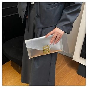 Close-up of metallic envelope clutch bag featuring a gold buckle and brushed silver texture
