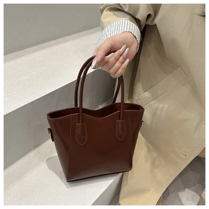 Detailed view of deep brown leather bucket bag with embossed fashion text and metal buckles