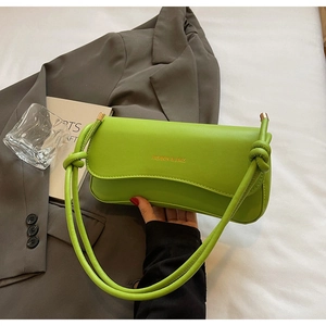 Detail of bright green faux leather shoulder bag featuring knotted strap and gold lettering