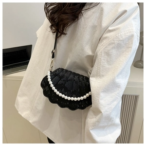 Detail of black shell crossbody bag with snake texture and elegant pearl handle strap