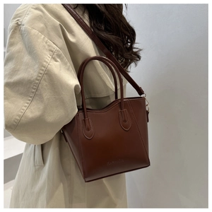 Détail d'un sac seau en cuir marron montrant la finition mate et le logo FASHION embossé