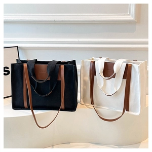 Detail of canvas tote bags with contrast leather handles and embossed fashion text