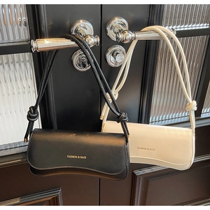 Detail of minimalist leather baguette bags in black and beige with knotted cord straps
