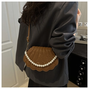 Detail of a brown shell crossbody bag featuring a pearl chain strap and snakeskin texture