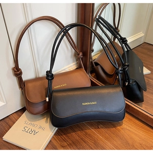 Close-up of minimalist leather shoulder bags with knotted straps and gold hardware