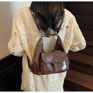 Detail of dark brown glossy backpack with metal buckle and shoulder straps