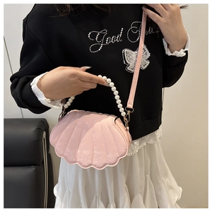 Pink shell-shaped crossbody bag featuring snake pattern texture and pearl handle detail