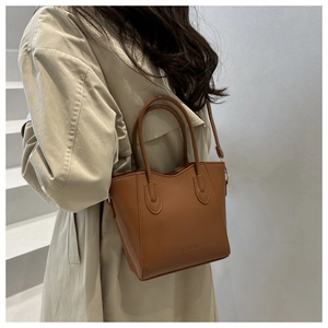 Close-up of brown leather bucket bag with embossed FASHION text and sleek handle