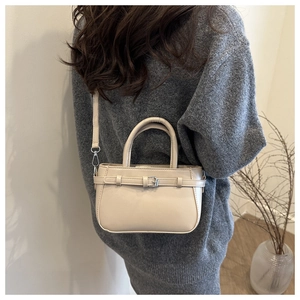 Mini sac carré beige chic porté en bandoulière, montrant la bandoulière et le cuir de qualité