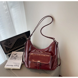 Close-up of a burgundy glossy leather crescent shoulder bag with a vintage buckle detail