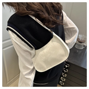 Détail du sac hobo blanc à motif serpent et boucle dorée porté par un mannequin