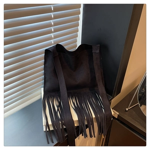 Détail d'un sac bandoulière en daim noir avec de longues franges bohèmes et une large sangle