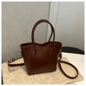 Close-up of brown leather bucket bag showing embossed Fashion text and polished texture
