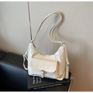 Detail of white glossy patent leather crescent bag featuring a silver buckle pocket
