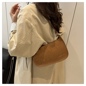 Détail d'un sac baguette marron avec texture serpent porté à l'épaule par un mannequin