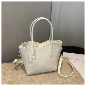 Detail of cream crossbody bucket bag with twin handles and fashion lettering on faux leather