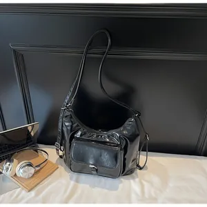 Detail of black glossy patent leather moon bag with silver buckle pocket and accessories