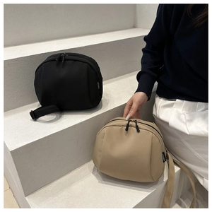 Detail view of nylon canvas shell crossbody bags in black and khaki with dual zippers