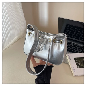 Detail of silver metallic underarm bag with drawstring closure and metal ring buckle