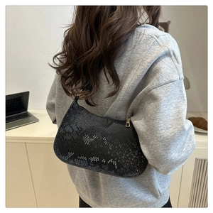 Détail du sac à bandoulière noir motif serpent avec fermeture éclair dorée en situation