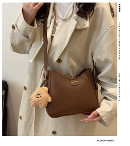 Detailed close-up of brown textured leather shoulder bag with plush star charm detail