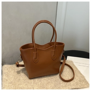 Close-up of brown bucket bag showing silver hardware and FASHION logo on plush surface
