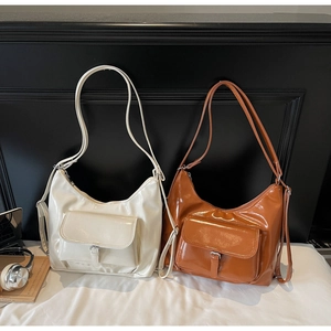 Detail of glossy PU leather shoulder bags with decorative buckle pockets and sleek zippers