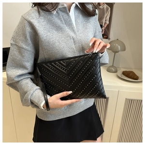 Détail de la pochette en cuir noir avec clous argentés en motif à chevrons