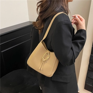 Elegant beige PU leather bucket bag with gold ring buckle and fringe detail on model