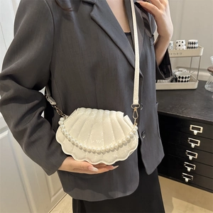 White shell shaped crossbody bag with pearl handle and minimalist faux leather texture