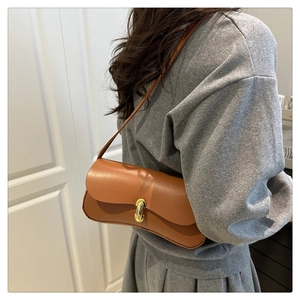 Detailed view of a brown faux leather baguette bag with golden metal cylindrical lock
