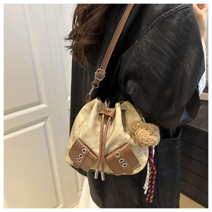 Detail of beige canvas bucket bag with brown leather pockets and cute bear charm
