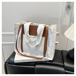 Detail of canvas tote bag featuring premium leather trim and sturdy dual handles