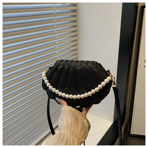 Detail of black shell-shaped bag with embossed snake texture and elegant pearl handle