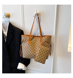 Dettaglio della borsa tote a scacchi con pochette coordinata su un gancio a muro