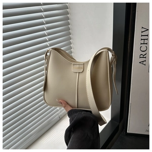 Detailed close-up of cream-colored shoulder bag with Fashion embossed leather label and seams