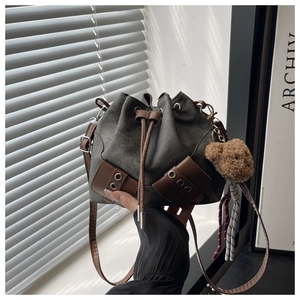 Detail of canvas bucket bag with leather drawstring and cute bear plush charm