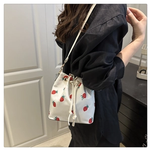 Lifestyle shot of a white bucket bag with strawberry print and drawstring closure