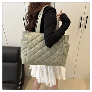 Detailed side view of a large quilted green tote bag showing texture and side pocket
