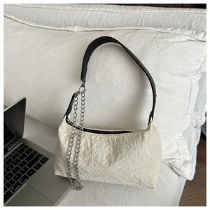 Détail du sac polochon en toile plissée blanche avec bandoulière noire et chaîne
