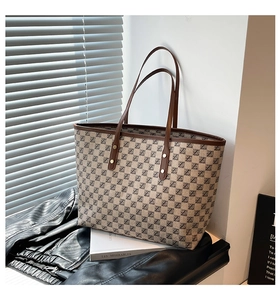 Detail of vintage tote bag with letter pattern print and brown leather handle
