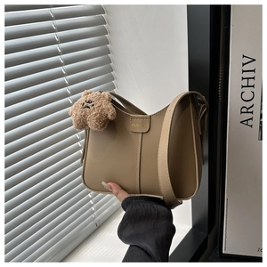 Detail of khaki PU leather shoulder bag featuring metal buckle and cute brown bear pendant